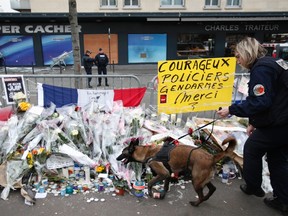A policewoman with a sniffer dog inspects the area in front of the Hyper Cacher kosher supermarket at the Porte de Vincennes in Paris January 21, 2015. Four people were killed in a hostage-taking situation during an attack by an Islamist militant on January 9. Placard reads, "Courageous Police and Gendarmes". (REUTERS/Charles Platiau)