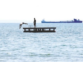 A laker passes by two boys cooling off in Lake Erie at Camelot Beach on a summer afternoon. (JULIE JOCSAK, QMI Agency)