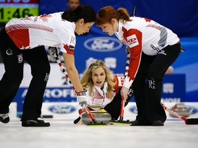 Canada skip Jennifer Jones (middle) delivers a rock as teammates Jill Officer (left) and Dawn McEwen sweep during their round-robin game against Finland at the World Women's Curling Championships in Sapporo March 14, 2015. ( REUTERS/Thomas Peter)