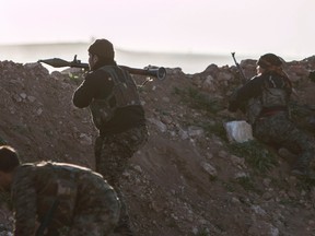 Kurdish People's Protection Units (YPG) fighters take positions behind a sand barricade as one of them aims an RPG  towards Islamic State fighters' position in the western countryside of Ras al-Ain March 10, 2015. Picture taken March 10, 2015. REUTERS/Rodi Said