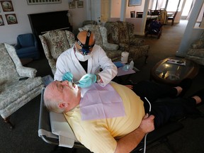 Mobile dental hygienist Hamid John works on patient John Wall. (Michael Peake/Toronto Sun)