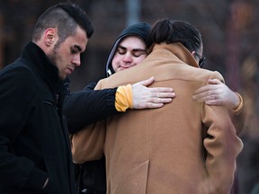 Mourners comfort one another during a vigil at Peace Garden Park for Demetrios Karahalios in Edmonton, Alta., on Sunday, March 15, 2015. Karahalios was found dead inside his Oliver home on March 8, 2014. Homicide detectives continue to search for Richard Joseph Lacarte, who is wanted on a Canada-wide warrant for the murder. Codie McLachlan/Edmonton Sun/QMI Agency