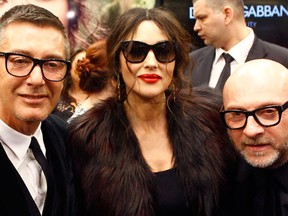 Domenico Dolce (R) and Stefano Gabbana (L) pose for a photograph with actress Monica Bellucci during the opening of a new Dolce&Gabbana shop in Moscow March 12, 2014.  (REUTERS/Ivan Burnyashev)