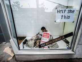 A child pretends to break rocks in a storefront window as part of World Vision public relations stunt in recognition of the UN World Day Against Child Labour event in Vancouver on  June 12, 2013.
 Photo By CARMINE MARINELLI / VANCOUVER 24HRS / QMI AGENCY