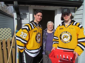 Mary Kirby receives a Meals on Wheels delivery from Sarnia Sting hockey players, from left, Justin Fazio and Noah Bushnell on Monday March 16, 2015 in Sarnia, Ont. (Paul Morden, The Observer)