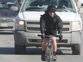 A cyclist rides through traffic on Portage Avenue. Several groups say fining cyclists who use their cellphone while riding is an idea worth considering. (Brian Donogh/Winnipeg Sun)