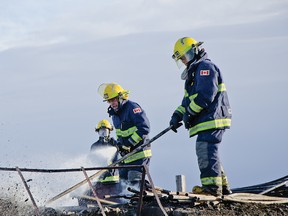 PCES members extinguish the remnants of a barn fire southwest of Twin Butte, Alta. on Saturday, March 14, 2015. While the fire is still under investigation the area's top firefighter indicated that the 110 km/h winds could have played a part in collapsing the barn. John Stoesser photo/QMI Agency.