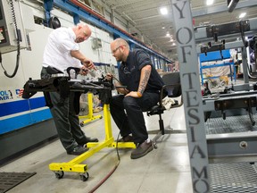 Technical sales representative Don Wilson, left, consults with operator Shawn Ridley as they make parts to be shipped to electric sports car maker Tesla at Attica Manufacturing on Invicta Court. (QMI Agency file photo)