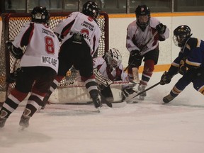 Goderich players Curtis McCabe (8) and Evan Buchanan (9) rush in to provide some help to their goalie Bryson Campbell as a Wingham player attempts to drive the puck home.