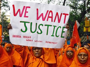 A Hindu nun holds a poster during a protest rally to show solidarity with the nun who was raped during an armed assault on a convent school, in Kolkata March 17, 2015. Indian Prime Minister Narendra Modi said on Tuesday he was "deeply concerned" about the rape of the elderly nun and the demolition of a church as protests for the better protection of women and religious minorities erupted across the country. REUTERS/Rupak De Chowdhuri