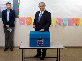 Israel's Prime Minister Benjamin Netanyahu  casts his ballot for the parliamentary election as his son Yair stands behind him at a polling station in Jerusalem March 17, 2015. Prime Minister Benjamin Netanyahu faced a fight for his political survival on Tuesday as Israelis voted in an election that opinion polls predict the centre-left opposition could win. REUTERS/Sebastian Scheiner/Pool