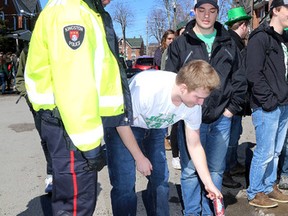 Kingston Police Const. Steve Koopman gets a St. Patrick's Day reveller to empty his beer on the street during a party on Aberdeen Street  in the University District near Queen's University Tuesday afternoon March 17 2015. There were about 1,000 people in the street celebrating the Irish holiday.  Ian MacAlpine/The Kingston Whig-Standard/QMI Agency