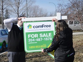 ComFree staffers affix a For Sale sign on a Winnipeg house March 18, 2015.