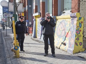 Police photograph a blood trail on the sidewalk after a 26-year-old man was stabbed in arm in downtown London, Ontario on Thursday, March 19, 2015. The victim was taken to hospital with non-life threatening injuries. Police are searching for suspect who ran south on Richmond St. (DEREK RUTTAN, The London Free Press)