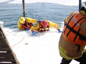 Sarnia firefighter Dave Gairns, left, helps firefighter and ice water rescue instructor Trevor Mitchell out of the water at the Sarnia Yacht Club during a training exercise Thursday. Assisting on the rope is firefighter Simon Sowkinski. (TYLER KULA/ THE OBSERVER/ QMI AGENCY)