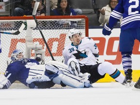 Maple Leafs goaltender Jonathan Bernier is knocked flat by Sharks' Logan Couture during Thursday night's game at the Air Canada Centre. (STAN BEHAL/TORONTO SUN)