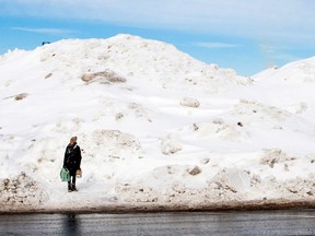 A pedestrian stands next to a mountain of snow in Halifax.

Scott Blackburn/QMI Agency