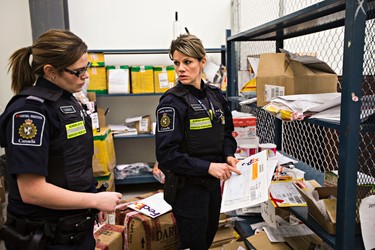 Border services officers Sonya Cudmore, left, and Jennifer Kennedy, right, look through confiscated items at the Canada Border Services Agency at the Edmonton International Airport in Leduc, Alta., on Thursday, March 5, 2015. Codie McLachlan/Edmonton Sun/QMI Agency