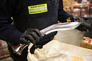 Border services officer Malcolm Hey inspects a Ghurka knife at DHL at the Edmonton International Airport in Leduc, Alta., on Thursday, March 5, 2015. Codie McLachlan/Edmonton Sun/QMI Agency