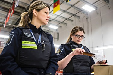 Border services officers Sonya Cudmore, left, and Jennifer Kennedy, right, check an incoming shipment at DHL at the Edmonton International Airport in Leduc, Alta., on Thursday, March 5, 2015. Codie McLachlan/Edmonton Sun/QMI Agency