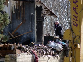 An investigator stands in the wreckage of a partially demolished home on McQueen Street Friday. Two people died as a result of the fire Thursday morning. (HEATHER RIVERS, Sentinel-Review)