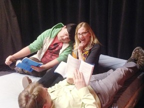 Cast members of Unnecessary Farce, Jordan Henry, Jenna Leifso, and Ron Plasschaert, rehearse their lines on a hotel room bed.