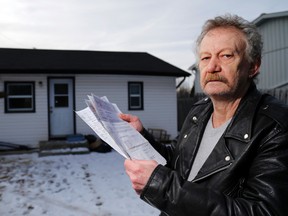 Gary Lowe holds his Hydro One bills outside his home in Bayside, Ont., on Jan. 21, 2015. (Luke Hendry/QMI Agency)