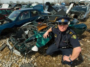 OPP Sgt. Dave Rektor with damaged cars at Corey Auto Wreckers in London, Ont. on Monday March 23, 2015. (MIKE HENSEN, The London Free Press)