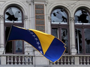 A Bosnian and Herzegovina national flag is seen on a damaged government building in Sarajevo February 8, 2014. Protesters across Bosnia set fire to government buildings and fought with riot police as long-simmering anger over lack of jobs and political inertia fuelled a third day of the worst civil unrest in Bosnia since a 1992-95 war. REUTERS/Antonio Bronic