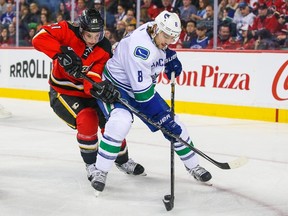 Vancouver Canucks defenseman Chris Tanev and Calgary Flames left wing Mason Raymond battle for the puck during the first period at Scotiabank Saddledome on Feb. 14, 2015. (Sergei Belski/USA TODAY Sports)