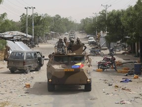 A convoy of soldiers from Niger and Chad drive down a looted street in the recently retaken town of Damasak, Nigeria, March 20, 2015. Soldiers from Niger and Chad who liberated the Nigerian town of Damasak from Boko Haram militants have discovered the bodies of at least 70 people, many with their throats slit, scattered under a bridge, a Reuters witness said. REUTERS/Emmanuel Braun