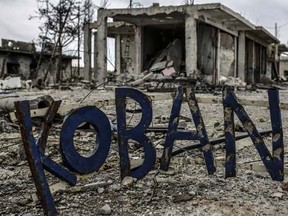 Destroyed building are seen around a sign that reads 'Kobane'  in the Syrian Kurdish town of Kobane, also known as Ain al-Arab, on March 24, 2015.    AFP PHOTO/YASIN AKGUL