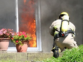 Flames poured out of an open patio door as firefighters tried to extinguish a fire in a home at 4520 Hwy. 2 near Gananoque in September 2011.