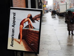 Pedestrians walk past an American Apparel sign outside one of their stores in New York in this April 1, 2011 file photo. The company's ousted its controversial founder Dov Charney as chairman effective immediately and moved to fire him as CEO and president following an ongoing investigation into alleged misconduct. (REUTERS/Lucas Jackson/Files)