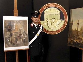A Carabinieri paramilitary policeman stands next to a painting of Luca Carlevarijs, right, and "Violin e bouteille de bass" painting of Pablo Picasso during a news conference in Rome, in this March 27, 2015 handout picture provided by Carabineri Press Office. (REUTERS/Carabinieri Press Office/Handout via Reuters)