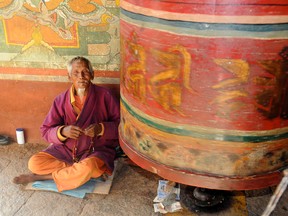 A monk collects donations beside a prayer wheel at Chimi Lhakhang — also known as the Temple of the Divine Madman — near Punakha, Bhutan, on Tuesday, Nov. 6, 2012. The temple was built in 1499 in honour of Buddhist saint Drukpa Kunley, who was known for his bizarre behaviour and unconventional teachings. (STEPHEN RIPLEY/QMI Agency)