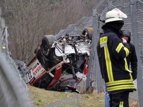 A member of the emergency services works at the scene where the Nissan of British driver Jann Mardenborough lays overturned outside the race track at the Nuerburgring on March 28, 2015. (AFP PHOTO/DPA)