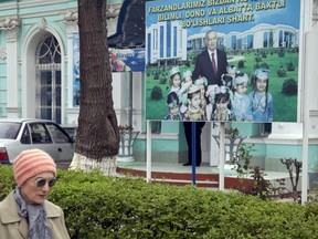 A woman walks past an election board of Uzbekistan's President Islam Karimov near a polling station in Tashkent, March 29, 2015. (Reuters/Stringer)