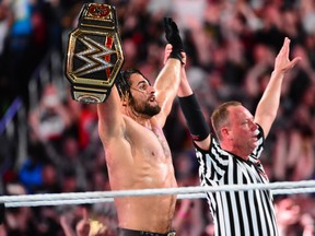 Seth Rollins holds up the WWE world heavyweight title belt.