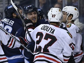 Winnipeg Jets centre Mark Scheifele (left) gets his gloves up with Chicago Blackhawks defenceman Johnny Oduya during NHL action at MTS Centre in Winnipeg, Man., on Sun., March 29, 2015. Kevin King/Winnipeg Sun/QMI Agency