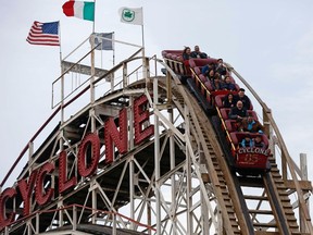 People ride the famous wooden roller coaster "Cyclone", before the arrival of Hurricane Sandy at Coney Island, New York in this October 27, 2012 file photo.  Dozens of people celebrating opening day with a free rollercoaster ride at New York's Coney Island amusement park on Sunday were forced to walked down the steep ride when it became stuck on the tracks, police said March 29, 2015.  REUTERS/Chip East/Files
