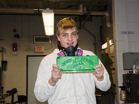 Eric Smyth, 14, displays a refurbished 1920s John Deere tractor name plate that he painted in a down draft spray booth simulator during experiential learning week. John Stoesser photo/QMI Agency.