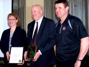 Sandra Alblas, left, a director with the Elgin Federation of Agirculture, and Fons Vandenbroek, right, EFA president, present Ken Monteith with a placque recognizing his induction into the Elgin Federation of Agriculture Hall of Fame Saturday at ceremony in St. Thomas. (PATRICK BRENNAN, For The Times-Journal)