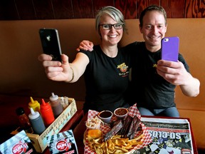 Ursula Krzepinski and Dean Braun from Memphis Blues Barbeque restaurant at 5317 - 23 Ave., in Edmonton take selfies in front of an Edmonton Sun newspaper and a plate of Full Slab o' Ribs. (Tom Braid/Edmonton Sun/QMI Agency)