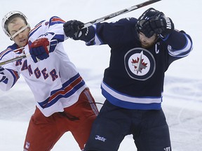Winnipeg Jets forward Andrew Ladd (right) knocks the helmet of New York Rangers centre Derek Stepan loose with a body check during NHL action at MTS Centre in Winnipeg, Man., on Tues., March 31, 2015. Kevin King/Winnipeg Sun/QMI Agency