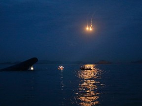 The South Korean Sewol ferry (L) is seen sinking in the sea off Jindo, as lighting flares are released for a night search, in this April 16, 2014 file photo.  REUTERS/Kim Hong-Ji/Files