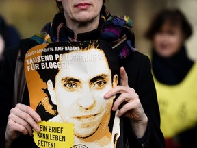 An Amnesty International activist holds a picture of Saudi blogger Raif Badawi during a protest against his flogging punishment on Jan. 29, 2015 in front of Saudi Arabia's embassy to Germany in Berlin. (AFP PHOTO/TOBIAS SCHWARZ)