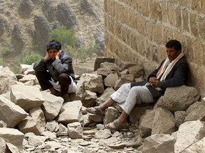 Yahya Haseen Al-Okeshe, right, a survivor sits next to his brother, near the rubble of their houses destroyed by an air strike in the Okash village near Sanaa on April 4, 2015. (REUTERS/Mohamed al-Sayaghi)