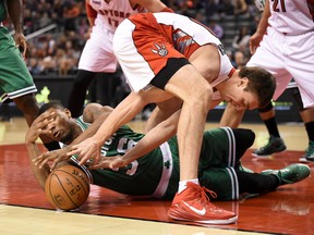 Raptors forward Tyler Hansbrough reaches back through his legs to battle for a loose ball with Celtics guard Marcus Smart during the first quarter at Air Canada Centre last night. (Dan Hamilton/Toronto Sun)