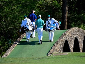 Golfers walk across the iconic Hogan Bridge at last year’s Masters. (Getty Images/AFP)